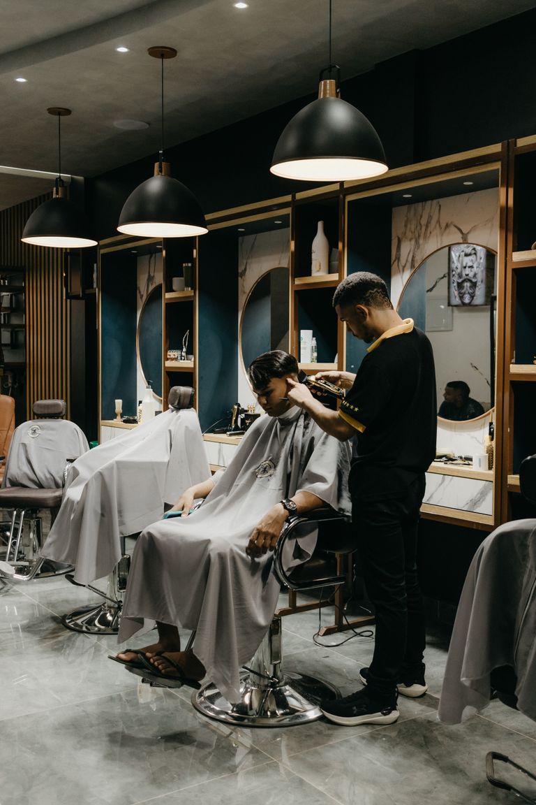 A professional barber giving a haircut to a client inside a stylish barbershop.