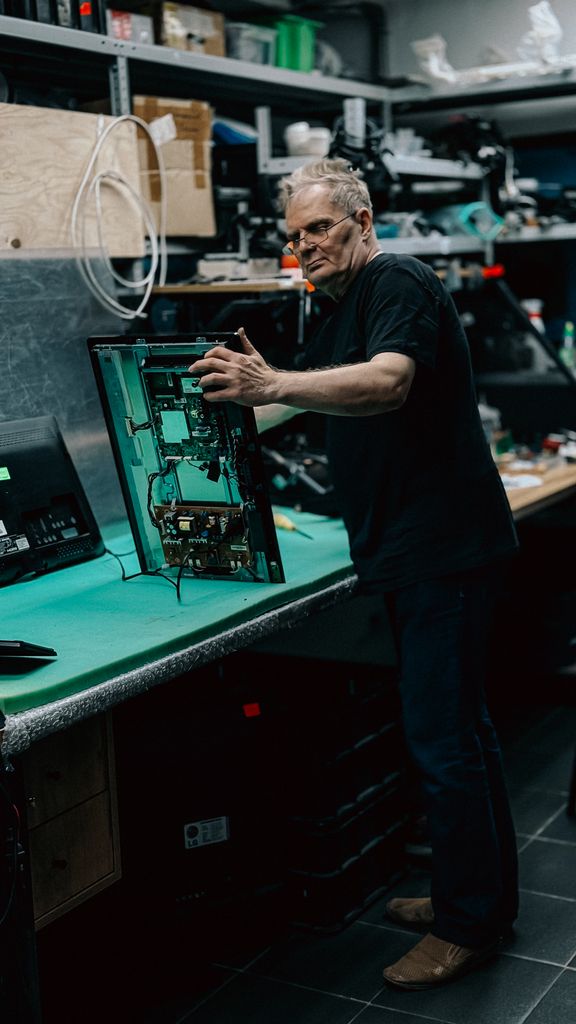 An experienced technician examines a circuit board at a workstation, showcasing technical expertise.
